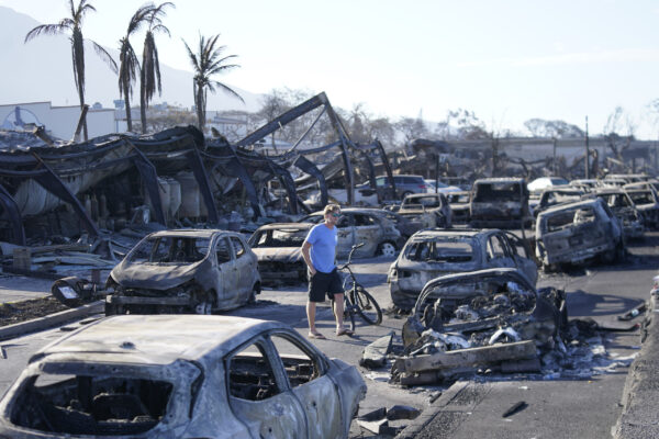 A man walks through wildfire wreckage Friday, Aug. 11, 2023, in Lahaina, Hawaii.  Hawaii emergency management records show no indication that warning sirens sounded before people ran for their lives from wildfires on Maui that wiped out a historic town.  (AP Photo/Rick Bowmer)